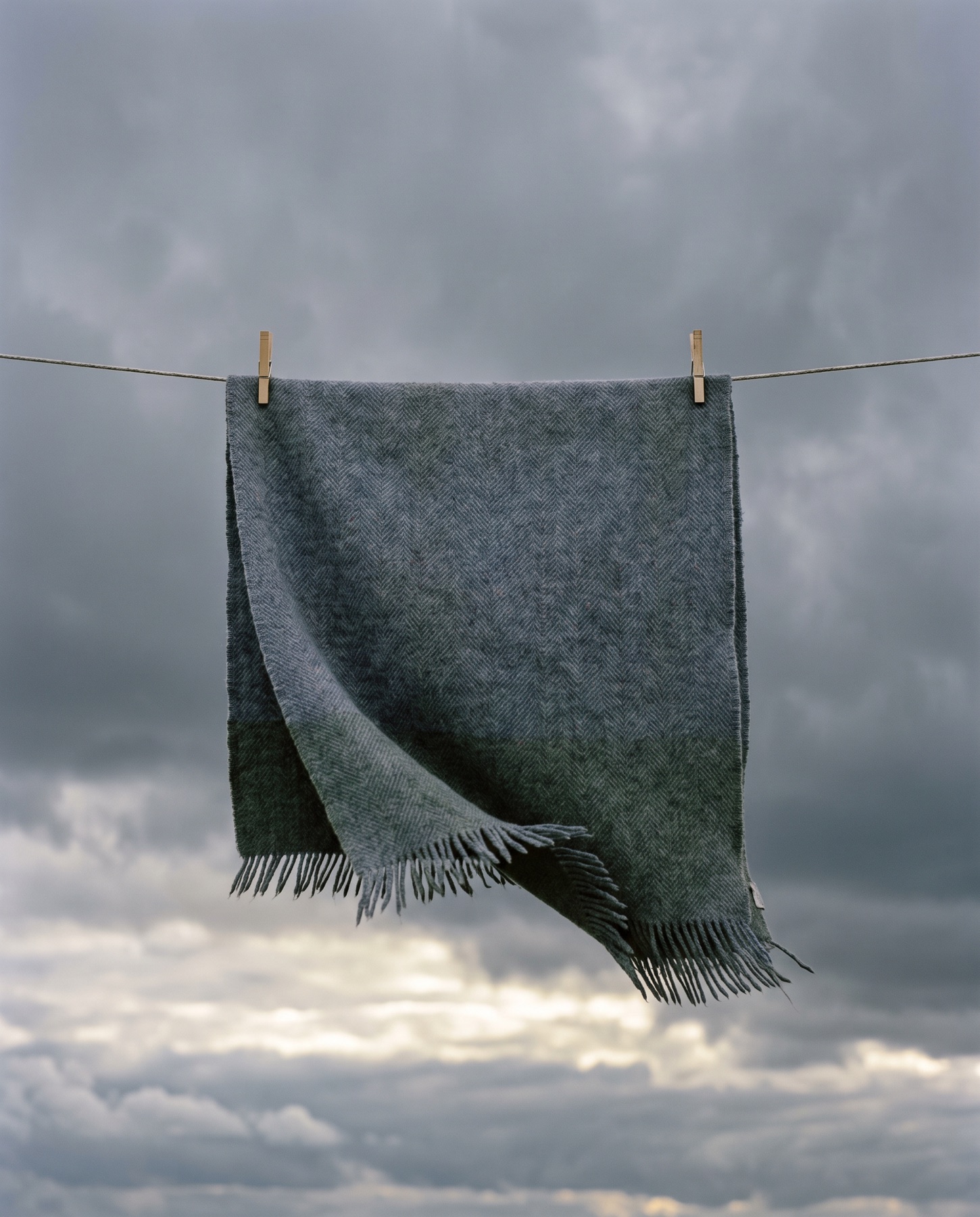 A heavy herringbone wool throw on the line against a storm-grey sky.